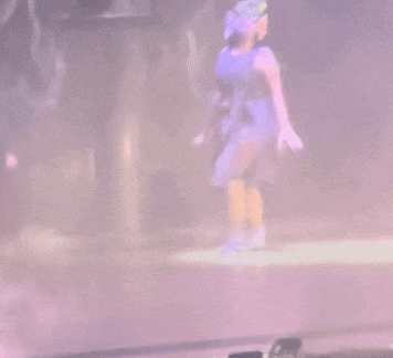 a woman in a purple dress is laying on the floor in front of a crowd