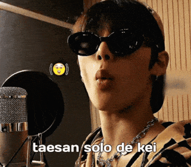 a man wearing sunglasses is singing into a microphone with taesan solo de kei written below him