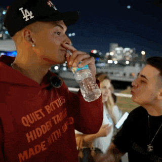a man wearing a la hat is drinking water from a bottle