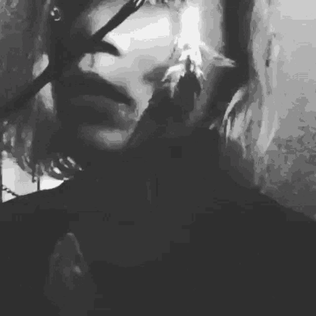 a black and white photo of a person 's face with a feather in it .