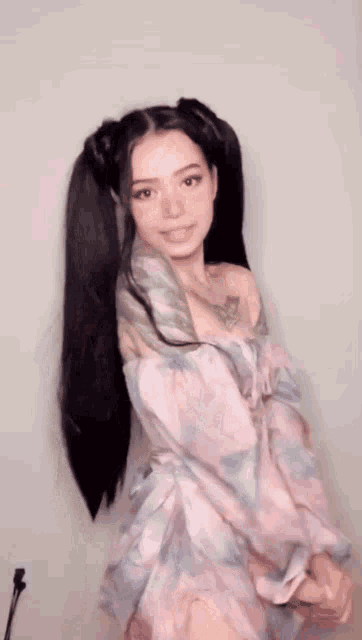 a woman with pigtails and tattoos is wearing a pink dress .