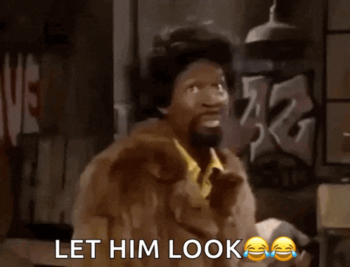 a man in a fur coat is holding his head and says let him look