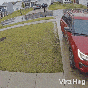 a woman is running towards a red car that says viralhog on the sidewalk