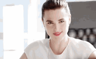a woman is wearing a white shirt and red lipstick and smiling .