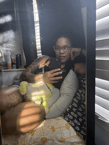 a woman is taking a selfie in front of a mirror with a pillow and a bottle of conditioner on the shelf
