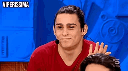 a man wearing a red shirt and a microphone with the words viperissima written above him
