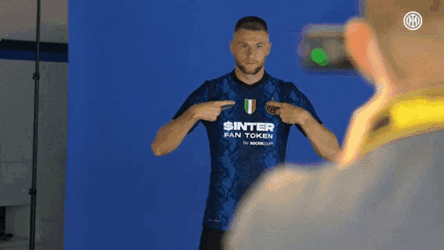 a man wearing a shirt that says $ inter fan token points to his chest