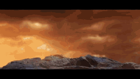 a rocky cliff with a sunset in the background