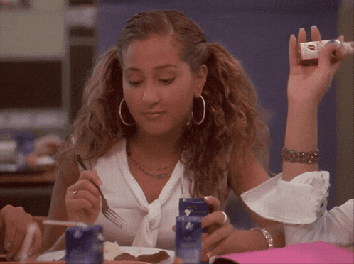 a woman sitting at a table with a fork in her hand holding a candy bar with a kiss on it