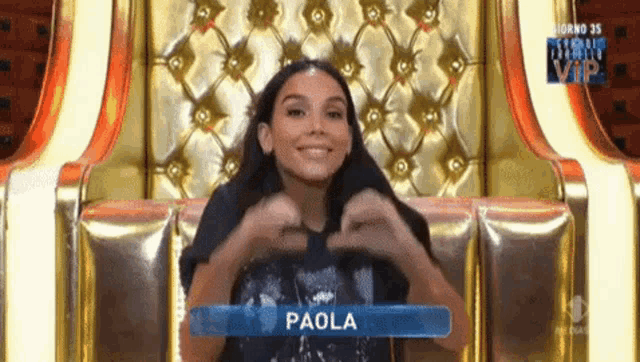 a woman is sitting in a chair with the name paola on her shirt
