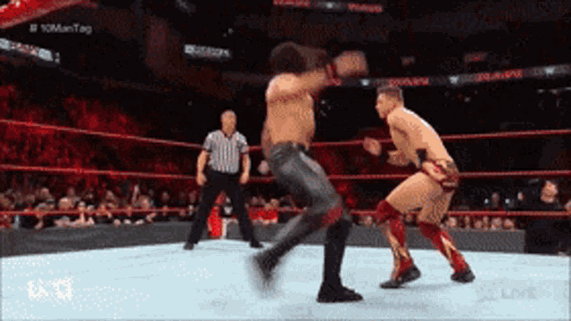 two wrestlers are fighting in a wrestling ring with a referee in the background