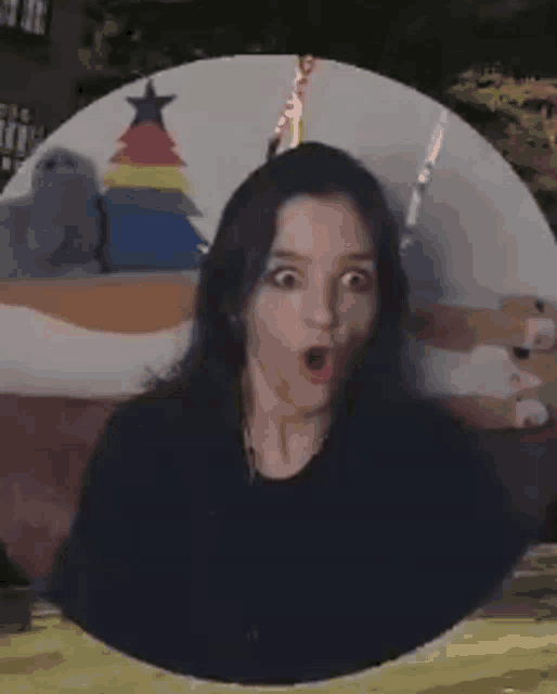 a woman with a surprised look on her face is standing in front of a christmas tree .