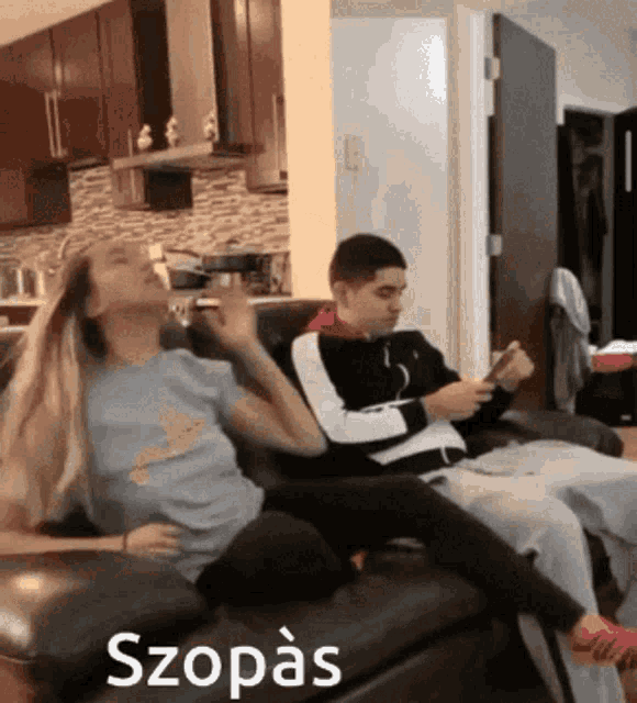 a man and a woman are sitting on a couch with the word szopas written on the bottom