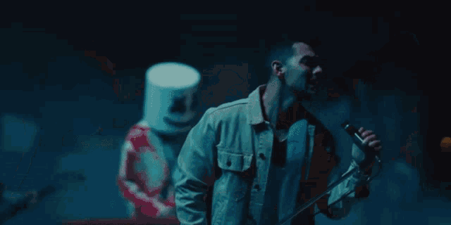 a man is singing into a microphone while a marshmallow man looks on