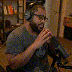 a man wearing headphones and a mickey mouse shirt is sitting in front of a microphone