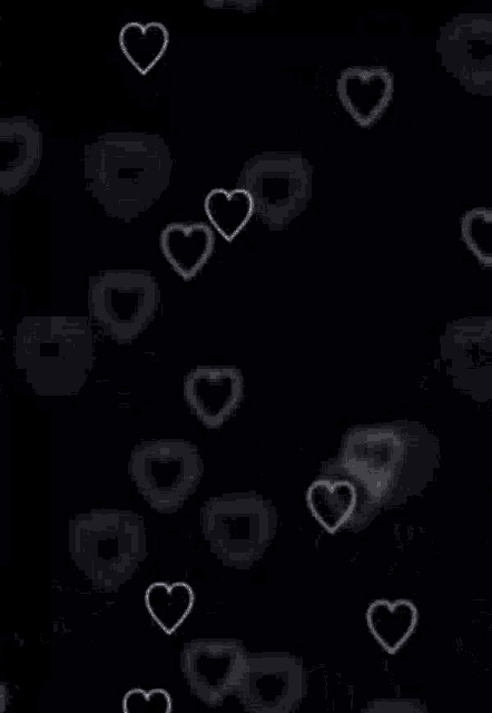 a black background with white hearts floating in the air .