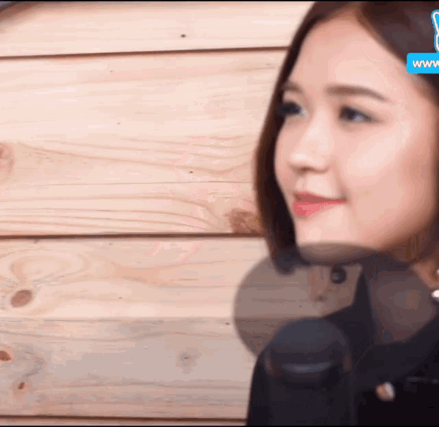 a woman wearing headphones is standing in front of a wooden wall ..