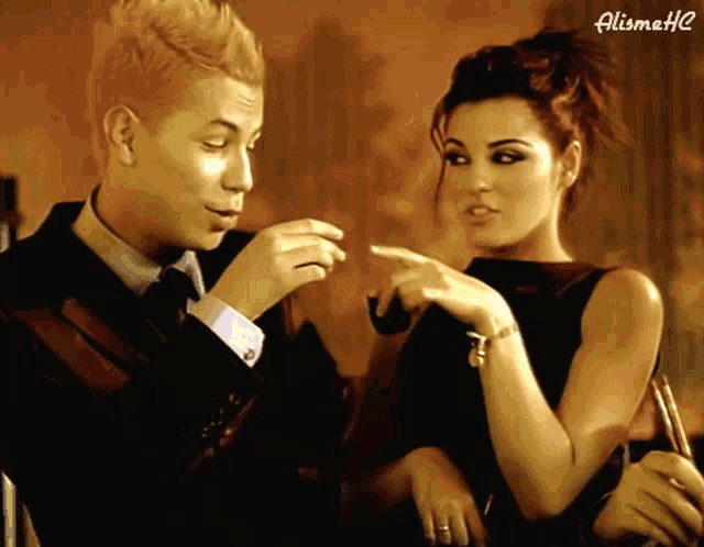 a man in a suit and tie is talking to a woman in a black dress who is pointing at him