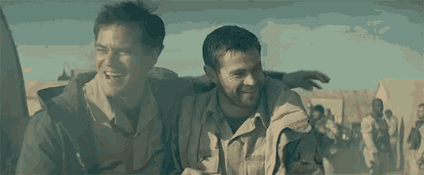 a man is carrying another man on his shoulders while walking in the desert .