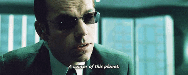a man in a suit and sunglasses says a cancer of this planet