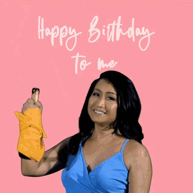 a woman in a blue top is holding a yellow towel and says happy birthday to me