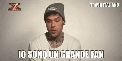 a man wearing a beanie and a white shirt is talking to someone .