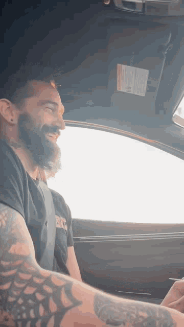 a man with a beard is driving a car