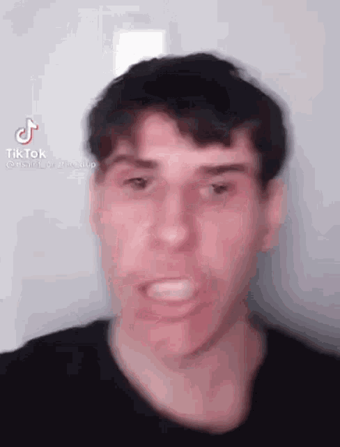a man in a black shirt is making a funny face while looking at the camera .
