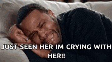 a man is crying while laying on a couch with his eyes closed .