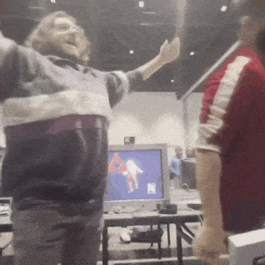 a man with his arms outstretched stands in front of a computer screen