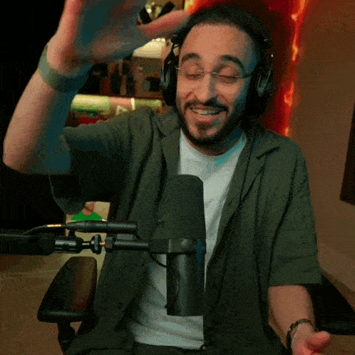 a man wearing headphones is sitting in front of a microphone and smiling