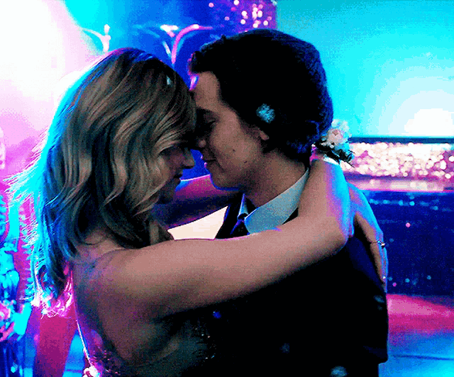 a man and a woman are hugging each other in a dark room
