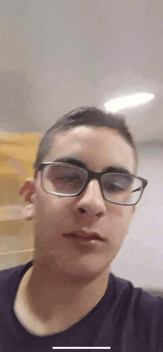 a young man wearing glasses and a black shirt takes a selfie