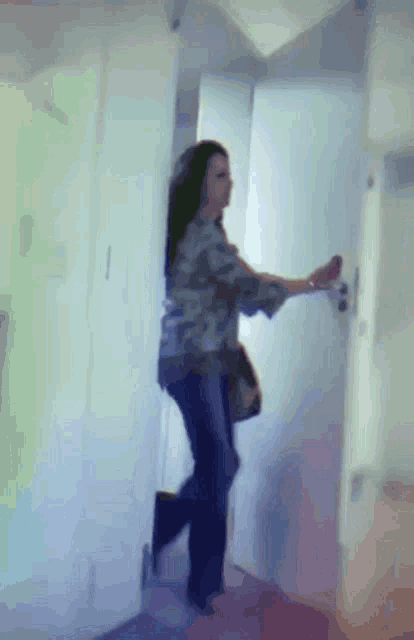 a woman is standing in a hallway holding a door handle