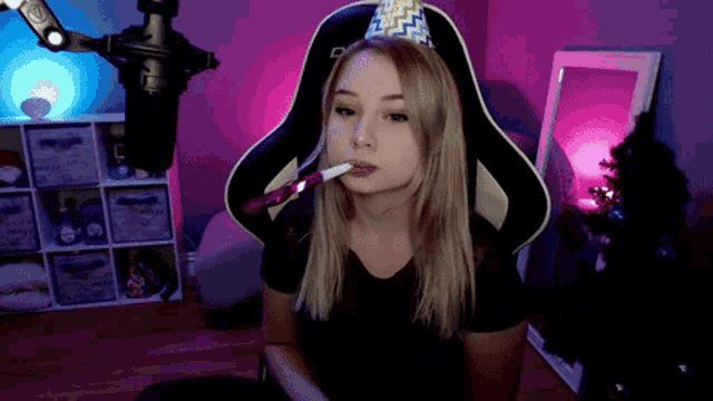 a woman wearing a party hat is blowing a whistle