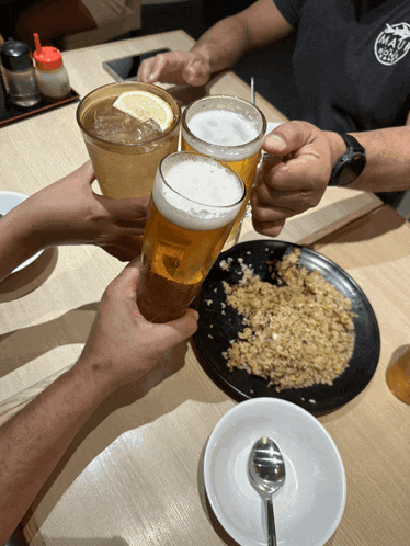 a man wearing a shirt that says ' hawaii ' on it toasts with a glass of beer