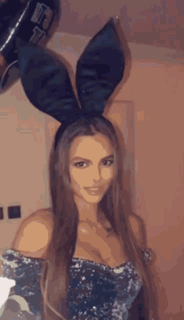 a woman is wearing bunny ears and holding a balloon with the letter f on it