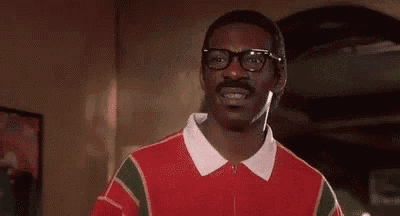 a man with glasses and a mustache is smiling in a room .