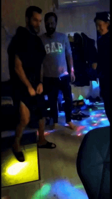 a man wearing a gap shirt is dancing in a dark room