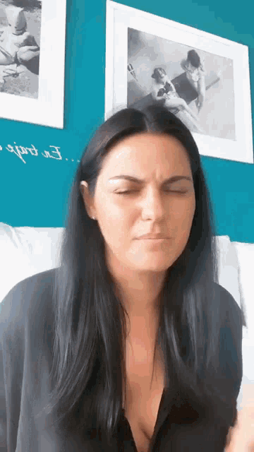 a woman sitting on a couch with her eyes closed in front of a wall with a picture of a baby on it