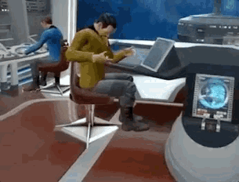 a man is sitting in a chair looking at his phone while another man sits at a desk