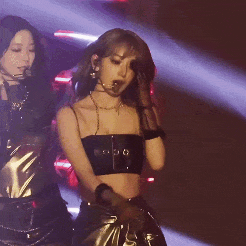 a woman in a black top and gold pants is dancing on stage
