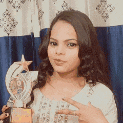 a woman is holding a trophy in front of a blue curtain