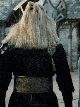 a woman with blonde hair is wearing a black coat and a belt that says artisanrabbit