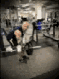 a man is lifting a barbell in a gym with a blurry background .