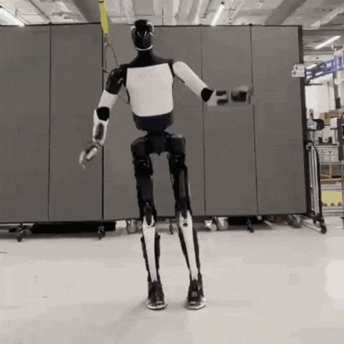 a black and white robot is standing in front of a wall that has the number 6 on it