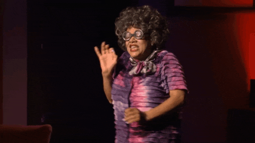 a woman wearing glasses and a purple dress is making a face