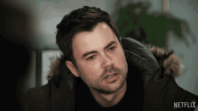 a man is wearing a jacket with a fur hood and a netflix logo on the bottom