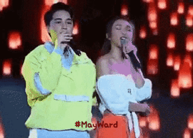 a man and a woman singing into microphones on a stage with #mayward written below them