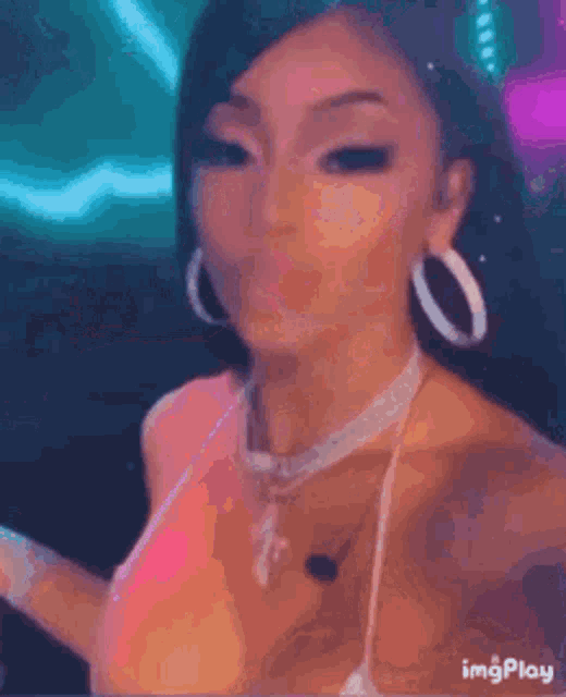 a woman wearing a pink bikini top and hoop earrings is taking a selfie .